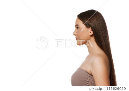 Side view portrait of young woman with long brown straight hair and perfect well-kept skin standing isolated on white background 115626020
