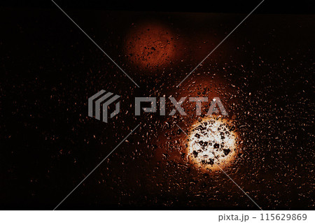 Raindrops and condensation on window at night with street lights. Cinematic dramatic background Raindrops and condensation on window at night with street lights. Cinematic dramatic background 115629869