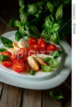 Mozzarella with basil and cherry tomatoes sprinkled with Mediterranean spices. 115630321