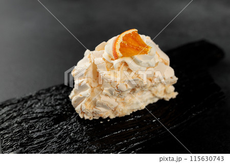 Meringue roll. Whipped proteins and sugar, filling - cream cheese based on soft cheese and cream on a black cutting board 115630743