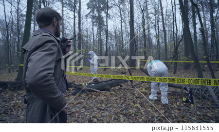 Police experts examining a murder scene in a gloomy forest, crime investigation 115631555