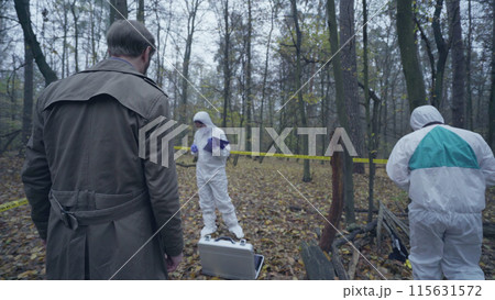 Skilled investigators visiting a crime scene outdoors, experts collecting evidence Skilled investigators visiting a crime scene outdoors, experts collecting evidence 115631572