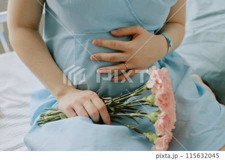 Pregnant woman touching her belly with love and holding beautiful bouquet of flowers Pregnant woman touching her belly with love and holding beautiful bouquet of flowers 115632045