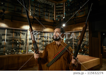 Hunter weapon shop client standing with rifles 115632274
