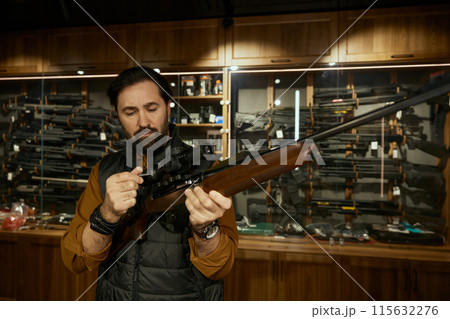 Man entrepreneur checking gun aiming telescopic sight at weapon store 115632276