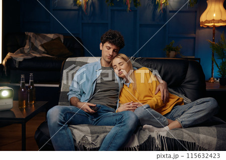 Loving couple fell asleep on a couch while watching a movie 115632423