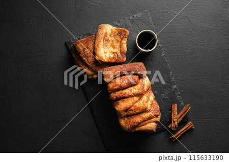 Cinnamon babka or brioche bread. Cinnamon slices bread with cup of espresso. Homemade pastry for breakfast. top view, black background, copy space Cinnamon babka or brioche bread. Cinnamon slices bread with cup of espresso. Homemade pastry for breakfast. top view, black background, copy space 115633190