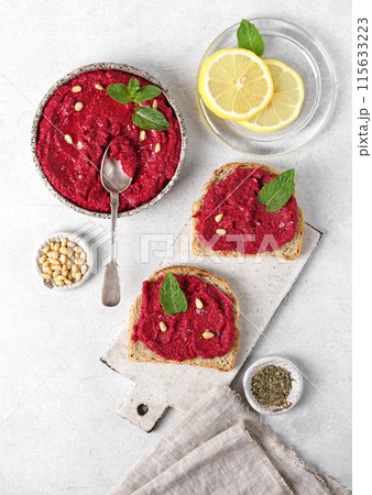 beetroot hummus in a bowl garnished with pine nuts and mint leaves. Served with lemon, top view beetroot hummus in a bowl garnished with pine nuts and mint leaves. Served with lemon, top view 115633223