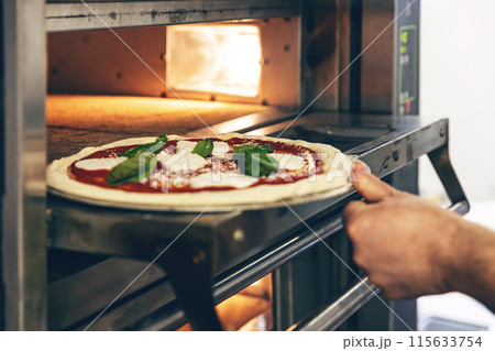 Fresh pizza placed in oven Fresh pizza placed in oven 115633754