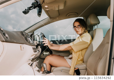 A woman in a yellow shirt is driving a car. She is wearing glasses and has her hands on the steering wheel A woman in a yellow shirt is driving a car. She is wearing glasses and has her hands on the steering wheel 115634292