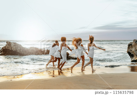 Happy young female friends having fun and celebrating hen party while running on the beach at the sunset, enjoying evening at coastline, free space Happy young female friends having fun and celebrating hen party while running on the beach at the sunset, enjoying evening at coastline, free space 115635798