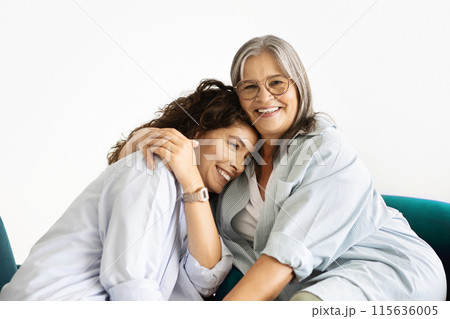 Cheerful pretty caucasian old woman hug millennial lady, sit in armchair, isolated on white studio background. Female generation, love, relationship, support and family at home Cheerful pretty caucasian old woman hug millennial lady, sit in armchair, isolated on white studio background. Female generation, love, relationship, support and family at home 115636005