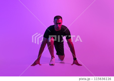 Front View Of Motivated African American Runner Guy Doing Crouch Start And Looking At Camera, Sportsman Posing Ready For Race On Purple Neon Background. Fit Man Preparing For Running Workout Front View Of Motivated African American Runner Guy Doing Crouch Start And Looking At Camera, Sportsman Posing Ready For Race On Purple Neon Background. Fit Man Preparing For Running Workout 115636116