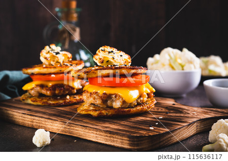Keto burgers on cauliflower fritters with cutlet, tomato and cheese on a board 115636117