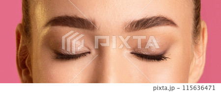 This image shows a close up of a woman eyelids, with defined eyebrows and subtle eye makeup. The photo is taken from a low angle, focusing on the upper eyelids and brow bones. 115636471