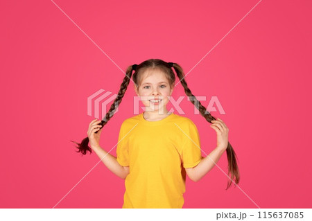 Portrait of cute cheerful little girl with braids posing over pink background, happy positive pre-teen female child wearing yellow t-shirt having fun and looking at camera, copy space Portrait of cute cheerful little girl with braids posing over pink background, happy positive pre-teen female child wearing yellow t-shirt having fun and looking at camera, copy space 115637085