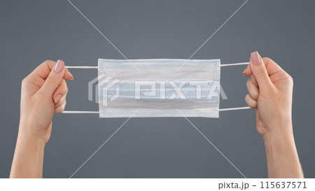 Female hands holding medical protective mask on grey background, panorama 115637571