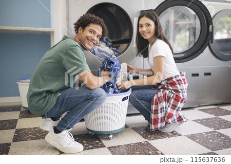 Happy Young Multicultural Couple Doing Laundry Together Loading Washer Machine At Laundromat Room. Guy Washing His Clothes And Posing Smiling At Camera. Public Laundrette Service Happy Young Multicultural Couple Doing Laundry Together Loading Washer Machine At Laundromat Room. Guy Washing His Clothes And Posing Smiling At Camera. Public Laundrette Service 115637636