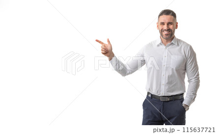 A smiling man dressed in business attire points confidently with his index finger against a clean, white background. The man exudes a professional yet approachable demeanor, copy space 115637721