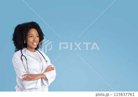Happy young black woman doctor therapist in white coat with crossed arms on chest looks at free space, isolated on blue studio background. Ad and offer, professional recommendation, health care Happy young black woman doctor therapist in white coat with crossed arms on chest looks at free space, isolated on blue studio background. Ad and offer, professional recommendation, health care 115637761