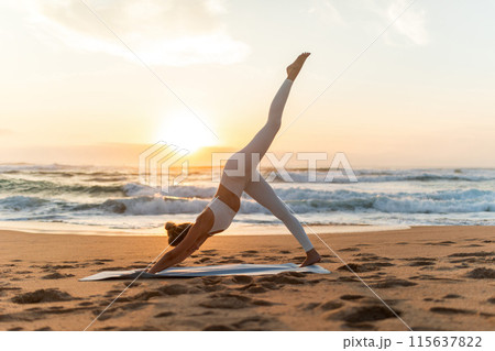 Young woman in sportswear doing yoga exercise with raised leg outdoors, having workout on sea beach at sunset, side view, full length. Lady stretching outside Young woman in sportswear doing yoga exercise with raised leg outdoors, having workout on sea beach at sunset, side view, full length. Lady stretching outside 115637822