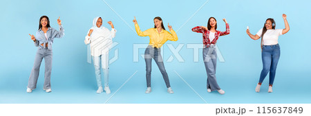 Smiling millennial diverse women in wireless headphones dancing, have fun with phone, enjoy fun, isolated on blue studio background, panorama, full length. Relax, lifestyle, ad and offer 115637849