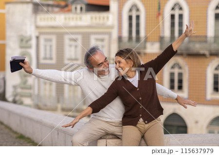 Travel To Portugal. Happy Senior Tourists Couple Posing Outdoors In Lisbon City, Spreading Hands Like Flying Airplane, Enjoying Traveling Together. Mature Spouses Having Fun During Holiday Tour Travel To Portugal. Happy Senior Tourists Couple Posing Outdoors In Lisbon City, Spreading Hands Like Flying Airplane, Enjoying Traveling Together. Mature Spouses Having Fun During Holiday Tour 115637979