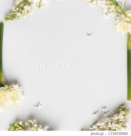 Spring flower frame made of white lilac and white daffodils on gray background with a place for text in the middle. Flat lay, copy space 115638068