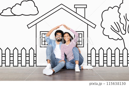 Loving eastern family husband and wife sitting over drawn on white wall house, make a roof with hands and smiling. Real estate, mortgage concept 115638130