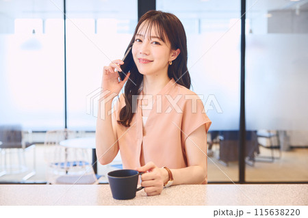 オフィスのパンドリーで電話をする女性 オフィスのパンドリーで電話をする女性 115638220