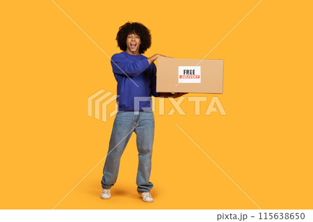 A man is standing and holding a box, which has a free delivery sign on it. He seems to be ready to deliver the package to a customer. 115638650