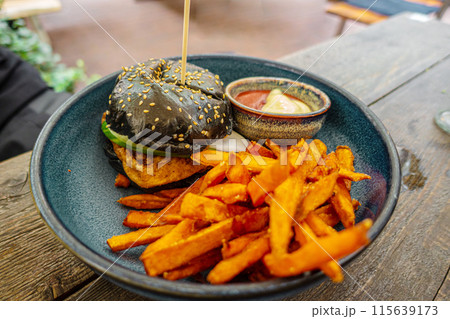 Black burger with french fries on wooden background. Black burger with french fries on wooden background. 115639173