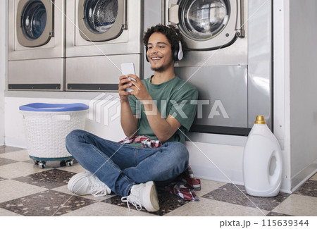 Easy Laundry. Happy Guy Using Smartphone Waiting While His Clothes Is Washing In Washer Machine, Enjoying Weekend Leisure And House Chores At Public Laundromat Service Indoor Easy Laundry. Happy Guy Using Smartphone Waiting While His Clothes Is Washing In Washer Machine, Enjoying Weekend Leisure And House Chores At Public Laundromat Service Indoor 115639344