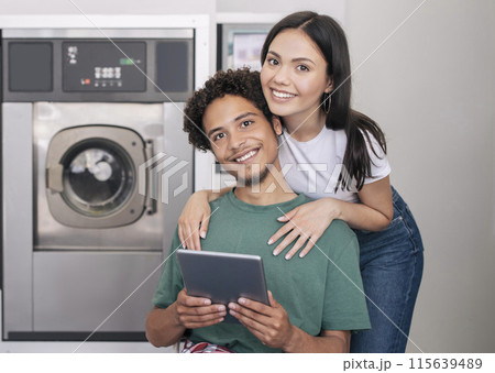 Laundry Service. Happy Young Diverse Couple Posing With Digital Tablet Hugging Near New Washing Machine Indoors, Booking Washer And Smiling To Camera Advertising Laundromat Service Laundry Service. Happy Young Diverse Couple Posing With Digital Tablet Hugging Near New Washing Machine Indoors, Booking Washer And Smiling To Camera Advertising Laundromat Service 115639489