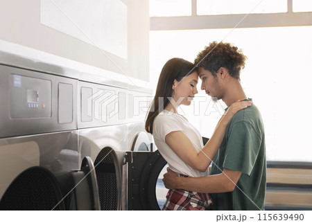 Laundry Advertisement. Loving Mixed Couple Hugging Standing Near Laundromat Washing Machines Indoor. Young Spouses Posing At Public Laundrette Washing Their Clothes On Weekend Laundry Advertisement. Loving Mixed Couple Hugging Standing Near Laundromat Washing Machines Indoor. Young Spouses Posing At Public Laundrette Washing Their Clothes On Weekend 115639490
