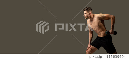 A man is actively engaged in a dumbbell exercise, lifting weights with focused determination against a plain gray background, panorama with copy space A man is actively engaged in a dumbbell exercise, lifting weights with focused determination against a plain gray background, panorama with copy space 115639494