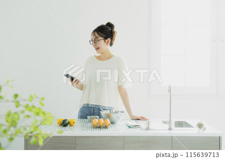 キッチンでスマホを見る若い女性 キッチンでスマホを見る若い女性 115639713