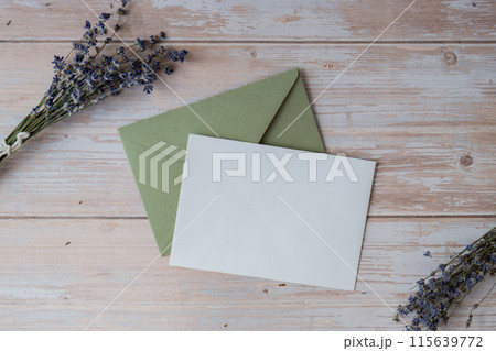 Flat lay composition of white paper greeting card on envelope with dry lavender flowers. Copy space template mock up. Top view. Concept of Wedding invitation postcard. Business advertisement Flat lay composition of white paper greeting card on envelope with dry lavender flowers. Copy space template mock up. Top view. Concept of Wedding invitation postcard. Business advertisement 115639772