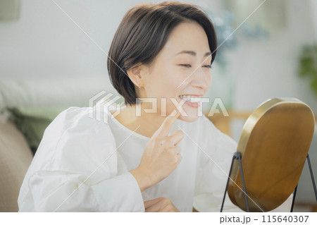 リビングで鏡を見るミドルの女性 リビングで鏡を見るミドルの女性 115640307