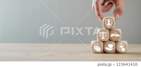 Wooden blocks with legal and medical icons arranged in a pyramid by a hand, representing personal injury law, legal protection, justice, and healthcare services. Wooden blocks with legal and medical icons arranged in a pyramid by a hand, representing personal injury law, legal protection, justice, and healthcare services. 115641410