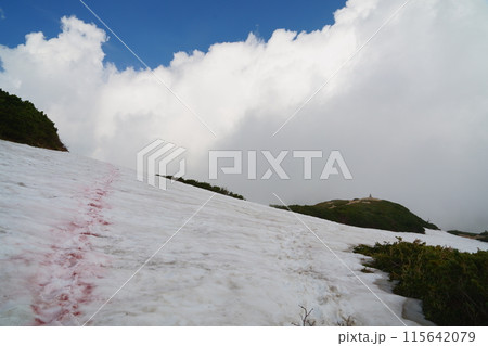 雲湧く丸山ケルンに向かう登山道　雪に示した登山コース 115642079