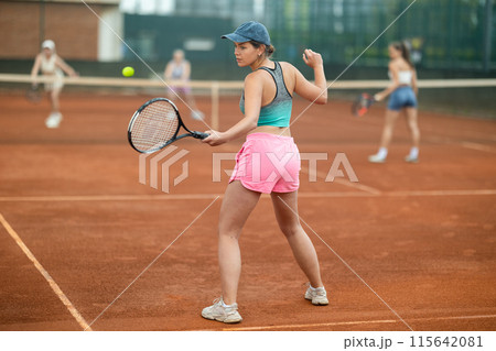 Emotional fit young girl playing doubles tennis on outdoor court 115642081