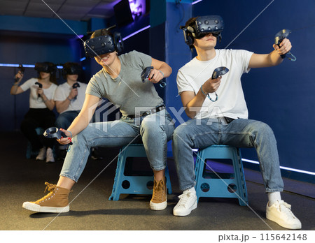 friends in helmets and with joysticks are sitting playing 3d action game. entertainment club 115642148