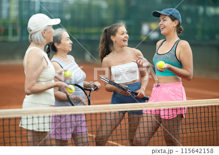 Cheerful female tennis players talking on outdoor court 115642158