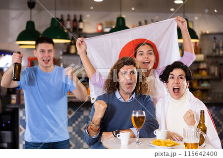 Group of happy fans celebrate victory of their favorite team with flag of Japan in beer bar 115642400