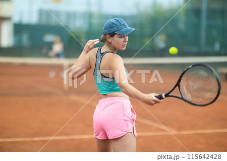 Young woman making serve while playing tennis 115642428