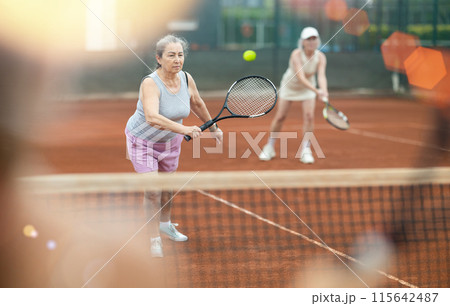 Two elderly women playing doubles tennis 115642487
