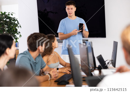 Young guy presenting educational mobile app to group of students 115642515