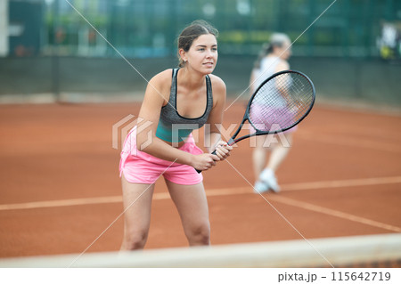 Focused girl playing doubles tennis on outdoor court Focused girl playing doubles tennis on outdoor court 115642719