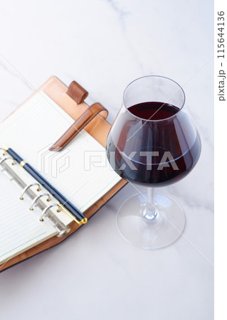 赤ワインを飲みながら、リング式のシステム手帳に日記をつけているイメージ写真 115644136